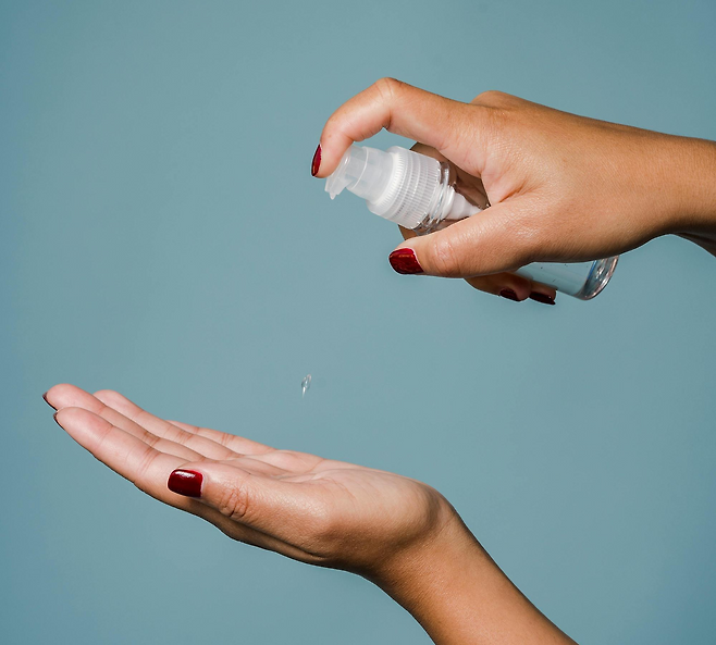 왼손을 펴고 있고 오른손으로는 펌핑 용기를 들고 있어 화장품을 손에 짜는 모습