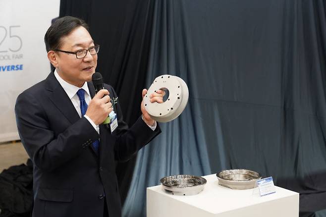 김원종 DN솔루션즈 대표이사가 2일 부산 벡스코(BEXCO)에서 열린 ‘DIMF2025’ DLX 언베일행사에서 적층제조로 제작된 부품을 들어보이고 있다.(사진=DN솔루션즈)
