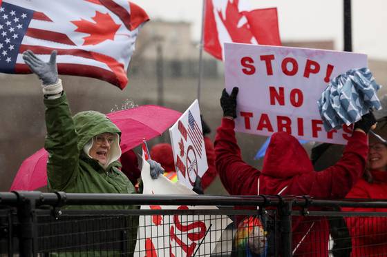 미국 뉴욕주 국경검문소에서 시위대가 ‘관세를 멈춰라’는 팻말을 들고 있다. [로이터=연합뉴스]