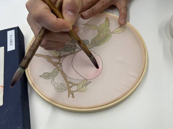 Jeong Hae-jin, director of Jinchae Lab, shows me how to add gradation effects to my jinchae, or silk painting, on March 28 at the studio in southern Seoul. [SHIN MIN-HEE]