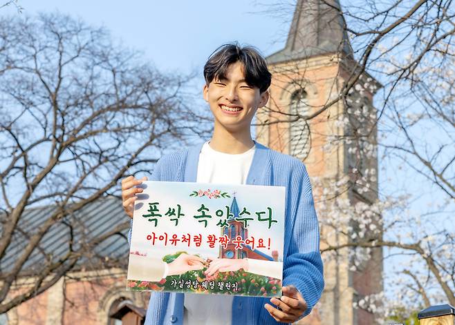 경북 칠곡군 가실성당 앞에서 순심고 1학년 김민준 학생이 푯말을 들고 ‘가실성당 웨딩 챌린지’홍보를 하고 있다.(사진제공-칠곡군)