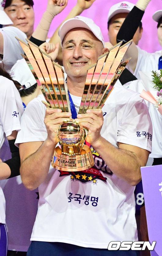 [OSEN=인천, 박준형 기자] 흥국생명 핑크스파이더스가 통산 5번째 챔피언결정전 우승을 차지했다. 김연경(37)은 현역 마지막 시즌을 통합우승으로 화려하게 장식했다.&nbsp;흥국생명은 8일 인천 삼산월드체육관에서 열린 ‘도드람 2024-2025 V-리그’ 챔피언결정전 5차전 정관장 레드스파크스와의 경기에서 세트스코어 3-2(26-24, 26-24, 24-26, 23-25, 15-13)&nbsp;승리를 거뒀다. 시리즈 전적 3승 2패로 마침내 5번째 우승에 성공했다.시상식 이후 흥국생명 아본단자 감독이 우승 트로피를 들고 포즈를 취하고 있다   2025.04.08 / soul1014@osen.co.kr