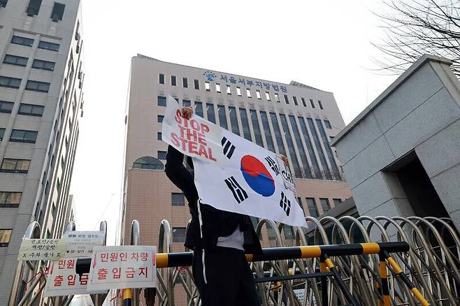 지난달 10일 오전 서울 마포구 서부지법에서 ‘서부지법 난동 사태’ 연루된 윤석열 전 대통령 지지자들이 재판을 받는다. 이날 서부지법 앞에서 탄핵 반대 지지자가 태극기를 들어 보인다. 정용일 선임기자 yongil@hani.co.kr