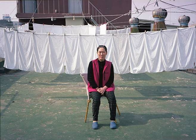 중국에서 온 동금옥 씨, 2015년. 경기도 시흥시의  한 모텔 손님들이 사용 후 세탁한 흰 수건들이 널려있다.  이곳에서 11개월을 일한 동 씨는 해고통지를 받았다. /사진가 심학철