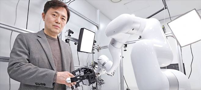 서울대 컴퓨터연구소 패러덱스 설비 공간에서 서진욱 서울대 컴퓨터연구소장이 로봇 손과 악수하고 있다. 이곳에서는 인간의 움직임을 여러 대의 카메라로 촬영해 동작을 모사하는 인공지능(AI) 모델을 개발하고 이를 로봇으로 재현하는 기술을 연구한다. /이솔 기자