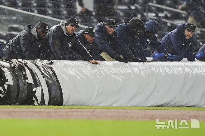 [뉴욕=AP/뉴시스] 12일(한국 시간) 미국 뉴욕 양키스타디움에서 열린 샌프란시스코 자이언츠와 뉴욕 양키스의 2025 메이저리그(MLB) 정규시즌 경기가 거센 비로 중단됐다. 6회 진행 도중 관계자들이 그라운드에 방수포를 깔고 있다. 2025.04.12.