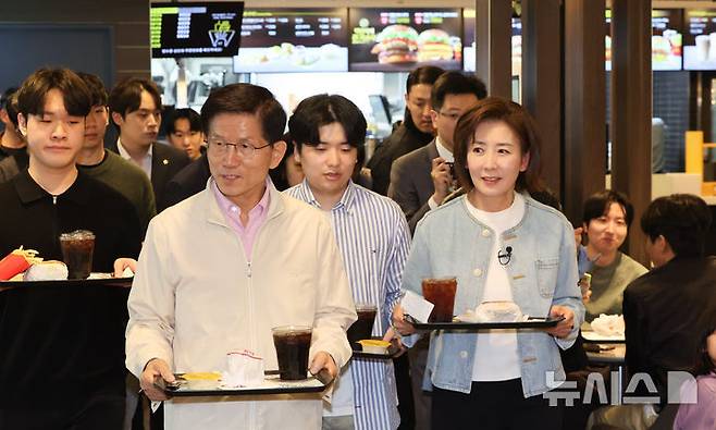 [서울=뉴시스] 황준선 기자 = 제21대 대통령선거 출마를 선언한 김문수 전 고용노동부 장관과 나경원 국민의힘 의원이 12일 오후 서울 동작구 맥도날드 중앙대학교점에서 학생들과 햄버거를 들고 이동하고 있다. 2025.04.12. hwang@newsis.com
