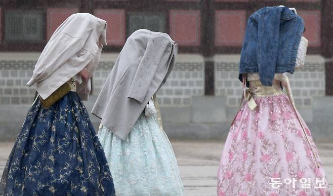 14일 오전 서울 종로구 경복궁에서 갑작스러운 비바람에 외국인 관광객들이 외투를 뒤집어쓴 채 발걸음을 재촉하고 있다. 송은석 기자 silverstone@donga.com