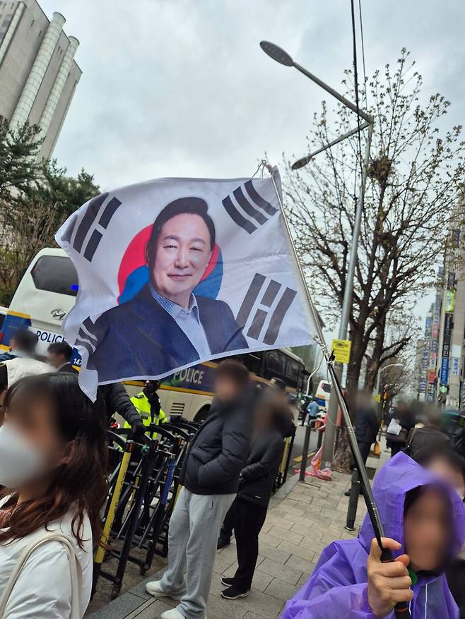 14일 서울 서초구 소재 서울중앙지방법원 건너편 인도에서 윤석열 전 대통령 지지자가 윤 전 대통령 얼굴이 크게 새겨진 대형 태극기를 흔들고 있다. 사진=김예지 기자