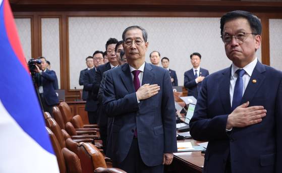 한덕수 대통령 권한대행 국무총리가 14일 정부서울청사에서 열린 국무회의에서 국기에 경례하고 있다. 오른쪽은 최상목 경제부총리 겸 기획재정부 장관.뉴시스