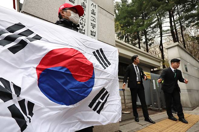 윤석열 전 대통령 첫 형사공판이 열린 14일 서울 서초구 서울중앙지법 앞에서 한 지지자가 태극기를 들고 서 있다. 연합뉴스