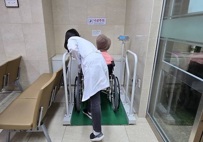서울의료원 의료진이 가로·세로 1m가 넘는 사각형 모양의 장치에 60대 여성 장애인이 탄 휠체어를 가볍게 밀어 올렸다. 거동이 불편한 장애인을 위한 체중계다. 김소연 기자 dandy@hani.co.kr