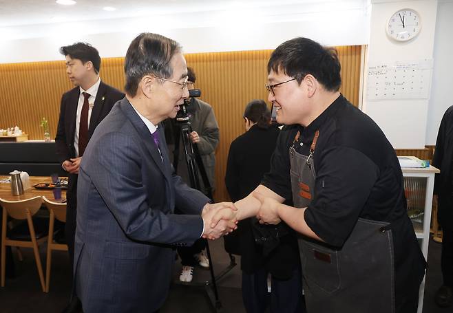 한덕수 대통령 권한대행 국무총리가 16일 결식 아동들에게 무료 점심을 제공해온 울산 뚠뚠이 돈가스에서 사장과 인사하고 있다./연합뉴스
