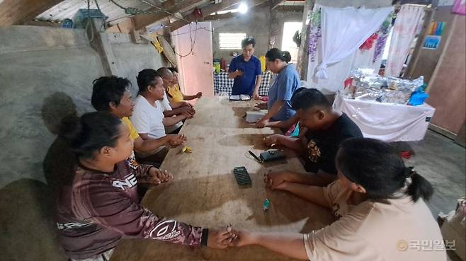 오태훈(가운데) 제주 국제순복음교회(박명일 목사) 장로가 지난해 1월 현마리사 집사의 필리핀 집을 함께 방문해 가족들과 만나 복음을 전한 뒤 손을 잡고 기도하고 있다. 국제순복음교회 제공