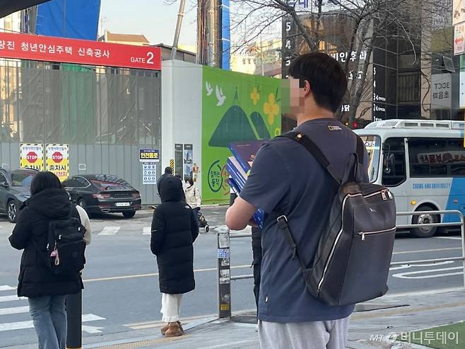 서울 동작구 노량진 학원가 일대에서 한 청년이 수험서 여러 권을 들고 있는 모습. /사진=이현수 기자.