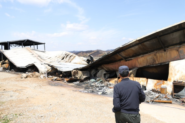 이달 15일 경북 청송군 진보면 한 사과밭 앞에서 한 농민이 산불로 전소된 저온 저장창고를 바라보고 있다. 연합뉴스