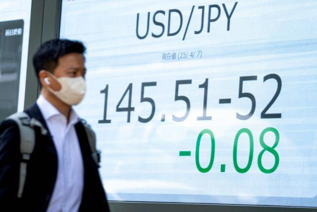 한 일본인이 지난 7일 도쿄에서 엔·달러 환율을 보여주는 전광판 앞을 지나가고 있다. 도쿄=AFP 연합뉴스