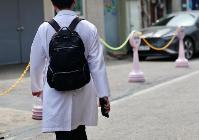 교육부가 내년도 의대 모집인원을 증원 이전인 3,058명으로 동결하겠다고 발표한 17일 서울시내 한 의과대학 인근에서 의대생이 이동하고 있다. 뉴시스