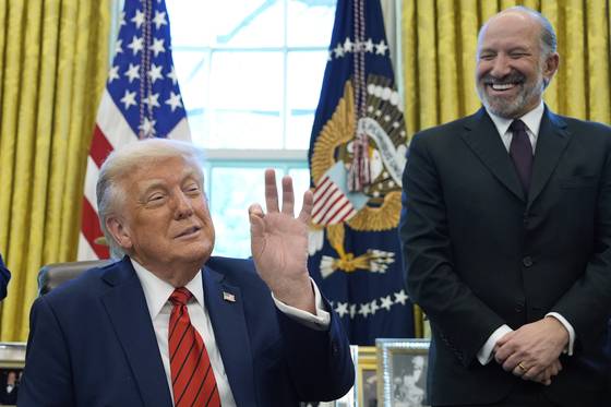 도널드 트럼프 대통령이 17일 백악관 집무실에서 행정명령에 서명하다 손가락으로 제스처를 취하고 있다. 보기에 따라 '돈'을 의미하는 뜻으로도 해석된다. 하워드 러트닉 상무부 장관이 트럼프 대통령의 행동을 보고 웃고 있다. AP=연합뉴스