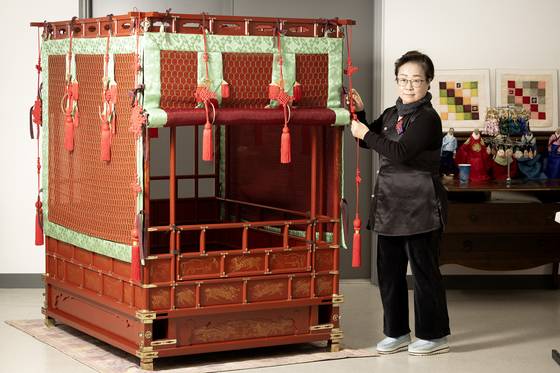 Park Hyun-ju, director of the Hanbok Technology Promotion Institute stands next to a palanquin in an office in Goyang, Gyeonggi, on April 2. [JUN MIN-KYU]