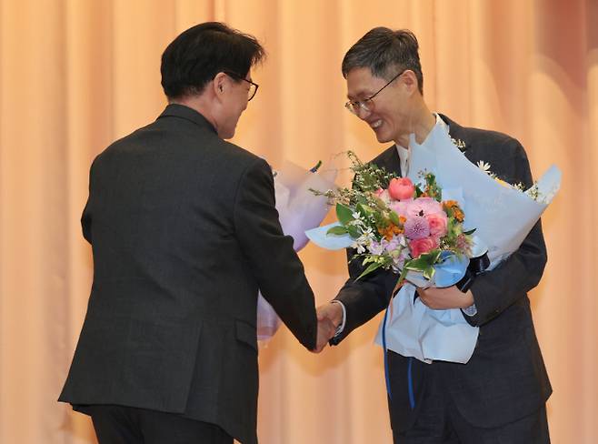 문형배 헌법재판소장 권한대행이 18일 서울 종로구 헌법재판소에서 열린 퇴임식에서 악수하며 축하 꽃다발을 받고 있다.  연합뉴스