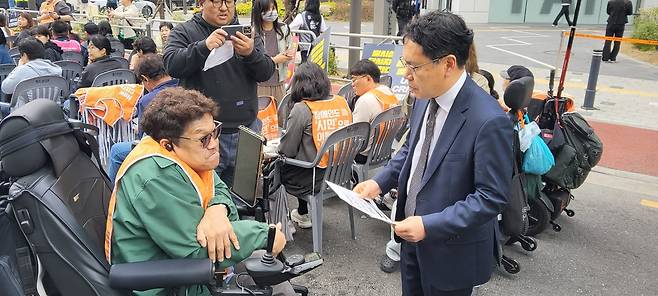 18일 ‘울산 태연재활원 인권참사 희생자 추모제’에 참가한 장애인이 손호준 보건복지부 장애인정책국장에게 ‘조규홍 복지부 장관 면담 요청서’를 전달하고 있다.  전장연 제공