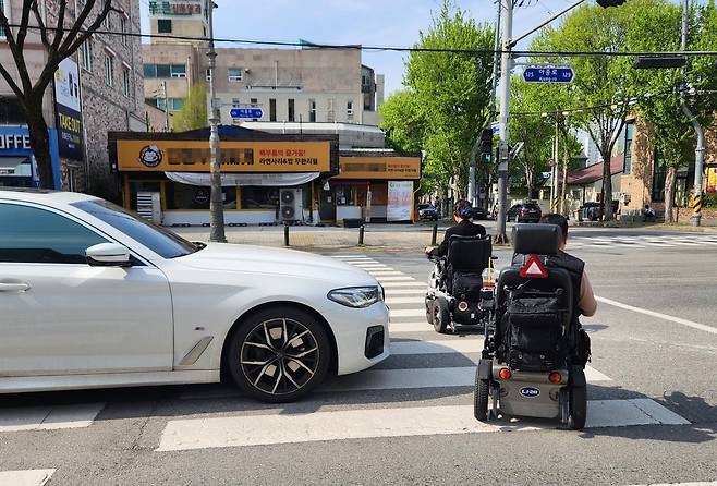 전동휠체어를 타고 횡단보도를 건너는 기자와 유승권 공동대표 [촬영 홍성란 활동지원사]