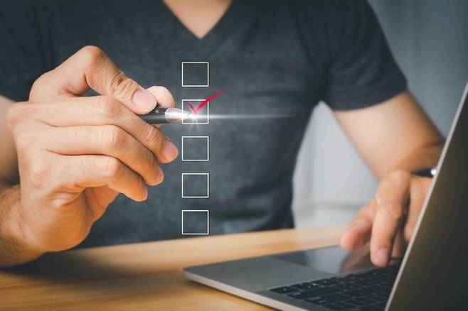 노트북 앞에 앉아있는 사람이 체크리스트 상자에 체크 표시를 하는 모습. 게티이미지뱅크