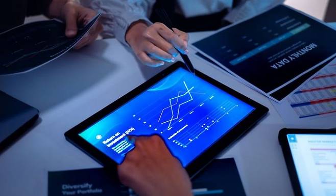 사람들이 책상 위에서 태블릿PC를 보며 회의를 하고 있다. 게티이미지뱅크