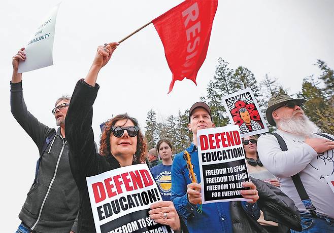 미국 버클리 캘리포니아대 캠퍼스에서 19일(현지 시간) 도널드 트럼프 행정부의 연방정부 보조금 지급 중단 및 삭감 압박에 반대하는 시위가 열렸다. 트럼프 행정부는 미 전역 60여 개 대학에 ‘반유대주의 척결’과 ‘DEI(다양성, 형평성, 포용성) 프로그램’ 중단을 요구하고 있다. 트럼프 대통령이 자신에 대한 비판 강도를 높이는 진보 진영에 대한 압박과 보수층의 규합을 위해 대학들을 공격하고 있다는 분석이 힘을 얻고 있다. 시위대가 “저항하자”는 문구가 적힌 깃발을 흔들고 있다. 버클리=AP 뉴시스