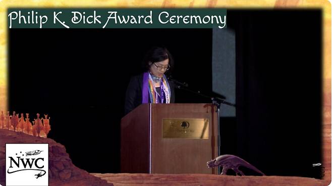 18일 저녁(현지 시각) 미국 시애틀 노웨스콘 47에서 열린 ‘2025 필립 K. 딕상’ 시상식에서 정보라 작가가 최종 후보에 오른 자신의 에스에프(SF) 단편집 ‘너의 유토피아’의 일부를 낭독하고 있다. 고 변희수 하사가 모티프가 된 ‘그녀를 만나다(To Meet Her)의 마지막 대목이다. 노웨스콘 유튜브 갈무리