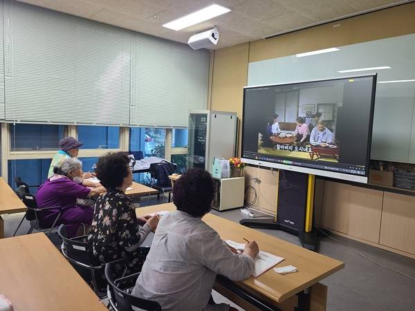 ▲ 치매관리 프로그램 '딩콕'을 통해 만든 영상을 시청하고 있는 모습. 사진=DOST11 제공.