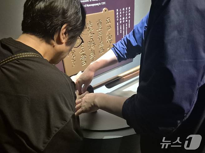지난 16일부터 이틀간 밀알복지재단은 13명의 시각, 청각 또는 시청각 장애인(장애 당사자), 활동지원사들과 함께 '오감만족 여행'을 진행했다.  국립해양유산연구소 목포해양유물전시관에서 재단 직원의 도움을 받아 '소소승자총통' 모형을 만져보는 한 당사자의 모습. 2025.4.17/뉴스1 ⓒ News1 남해인 기자