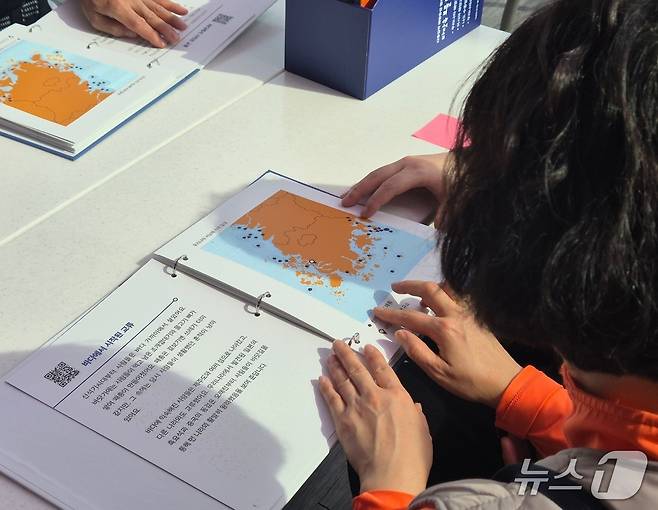 지난 16일부터 이틀간 밀알복지재단은 13명의 시각, 청각 또는 시청각 장애인(장애 당사자), 활동지원사들과 함께 '오감만족 여행'을 진행했다.  국립해양유산연구소 목포해양유물전시관의 점자 표기 도서를 읽는 한 당사자의 모습.  2025.4.17/뉴스1 ⓒ News1 남해인 기자