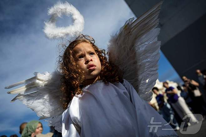 18일(현지시간) 푸에르토리코 산후안에서 천사 복장을 한 어린이가 성금요일 행사에서 종교 교구민들과 함께 걷고 있다. ⓒ AFP=뉴스1