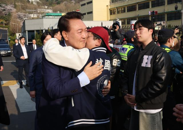 윤석열(왼쪽) 전 대통령이 헌법재판소의 파면 결정 일주일 만인 11일, 서울 용산구 한남동 대통령 관저를 떠나기에 앞서 정문 앞에서 자신을 지지하는 자유대학 소속 학생과 포옹하고 있다. 정다빈 기자