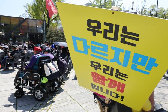 20일 오후 서울 종로구 마로니에 공원에서 장애인의 날을 맞아 열린 전국장애인차별철폐연대 전국집중결의대회에서 한 참가자가 전동휠체어에 피켓을 걸고 있다. 뉴스1