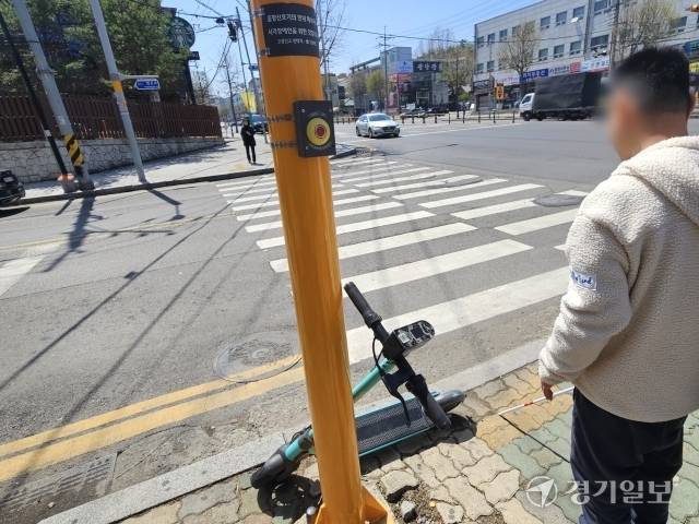 19일 오후 1시께 인천시 부평구 인천광명원 앞 도로. 시각장애인 A씨가 점자블록에 놓인 공유킥보드 때문에 음향신호기를 찾지 못하고 있다. 박기웅기자
