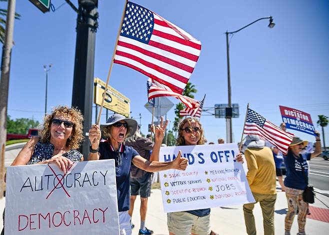 주말을 맞은 19일(현지시간) 미국 플로리다주 코코아에서 트럼프 행정부 정책에 반대하는 시민들이 ‘핸즈오프’(Hands Off·손 떼라)  푯말을 들고 시위를 벌이고 있다. <AFP 연합뉴스>