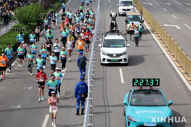 [베이징=신화/뉴시스] 19일 중국 베이징 이좡 경제기술개발구에서 열린 하프마라톤에서 인간과 로봇 참가자들이 나란히 달리고 있다. 2025.04.20