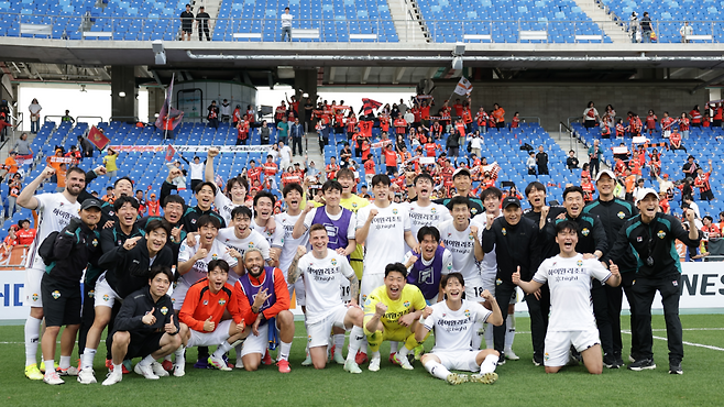 강원 FC 선수들이 지난 19일 울산에서 울산을 꺾은 뒤 서포터스를 배경으로 기념 사진을 찍고 있다. 프로축구연맹