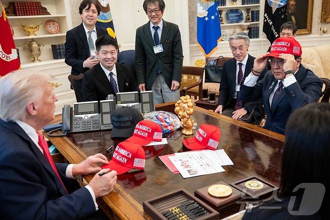 지난 16일(현지시간) 미국 워싱턴DC 백악관 집무실을 찾은 아카자와 료세이 일본 경제재생상이 도널드 트럼프 미국 대통령이 서명해 건네 준  '마가(MAGA, 미국을 다시 위대하게)' 모자를 써보고 있다.(출처 백악관) ⓒ News1 류정민 특파원