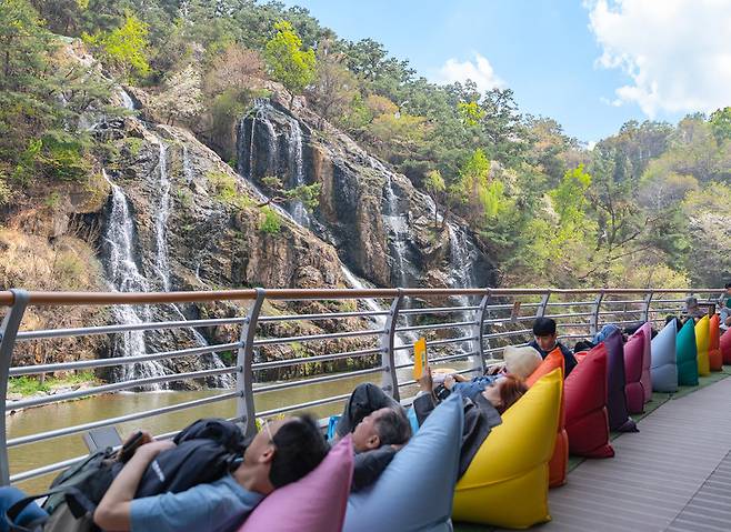 18일 서울 서대문구 홍은동 ‘카페폭포’ 테라스에서 외국인 방문객들을 비롯한 손님들이 홍제폭포를 감상하고 있다. 2023년 문을 연 카페폭포는 구가 직접 운영한다. 서대문구는 지난해부터 이 카페에서 벌어들인 수익금을 구내 학생들을 위한 장학금으로 쓰고 있다. 서대문구 제공