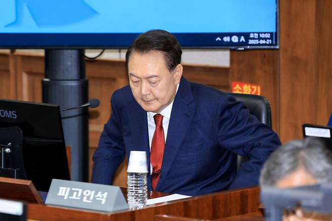 윤석열 전 대통령이 21일 오전 서울 서초동 서울중앙지법에서 열린 내란 우두머리 혐의 형사 재판 2차 공판에 출석해 피고인석에 앉고 있다. 사진공동취재단