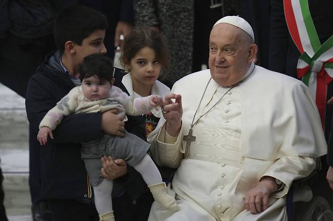 지난 2월 12일(현지시각) 프란치스코 교황이 바티칸 바오로 6세 홀에서 열린 주간 일반 알현에 참석한 어린이의 손을 잡고 있다. 바티칸/AP 연합뉴스