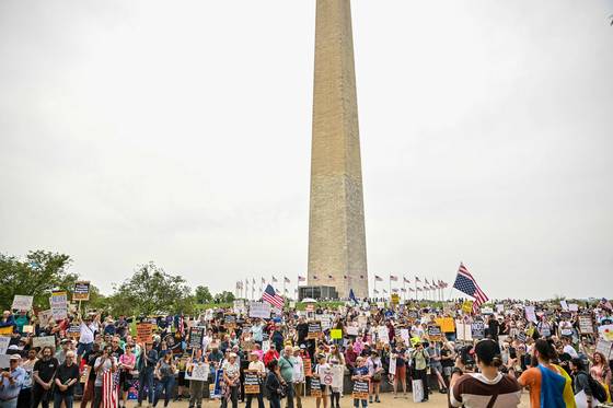 19일(현지시간) 도널드 트럼프 미국 대통령에 반대하는 시위가 열린 가운데 워싱턴DC에서 시위대가 백악관을 향해 행진하고 있다. 이들은 성조기를 거꾸로 흔들며 추방된 이민자의 송환을 촉구했다. [AFP=연합뉴스]