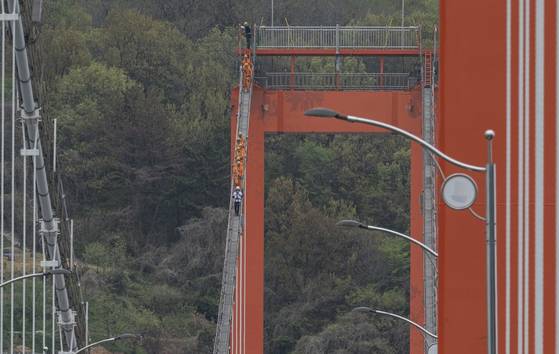 지난 19일 한국 최초 현수교인 경남 남해대교에서 열린 '브리지 클라이밍' 행사 참가자들이 다리 케이블을 따라 걸어 내려오고 있다. 사진 남해군