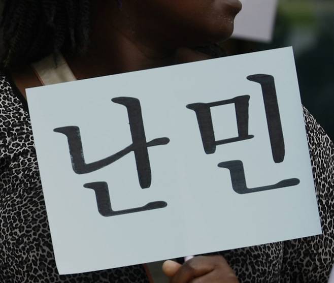 2022년 국내 체류 중인 한 난민신청자가 '난민'이라 적힌 문구를 들고 시위를 벌이고 있다./사진=뉴시스.