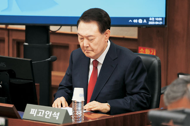 ‘내란 수괴 피고인’ 윤석열　 윤석열 전 대통령이 21일 오전 서울 서초구 서초동 서울중앙지법에서 열린 내란 우두머리(수괴) 혐의 재판의 두 번째 공판기일에 출석해 피고인석에 앉아 자료를 살펴보고 있다.   사진공동취재단