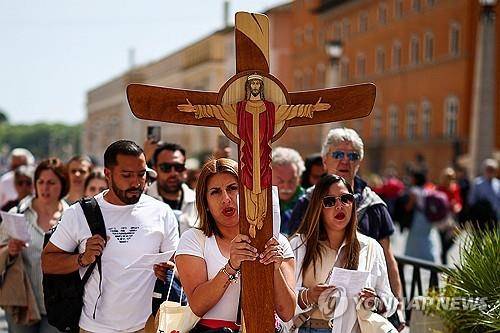 교황 선종 기리는 신도들 (로마 로이터=연합뉴스) 한 여신도가 21일(현지시간) 교황의 선종 소식을 들은 뒤 대형 십자가를 들고 성베드로 광장 근처를 행진하고 있다. 2025.04.21.